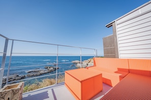 A balcony with a view of the ocean, featuring a white railing and orange seating. - XYZ speciale (Shirahama)