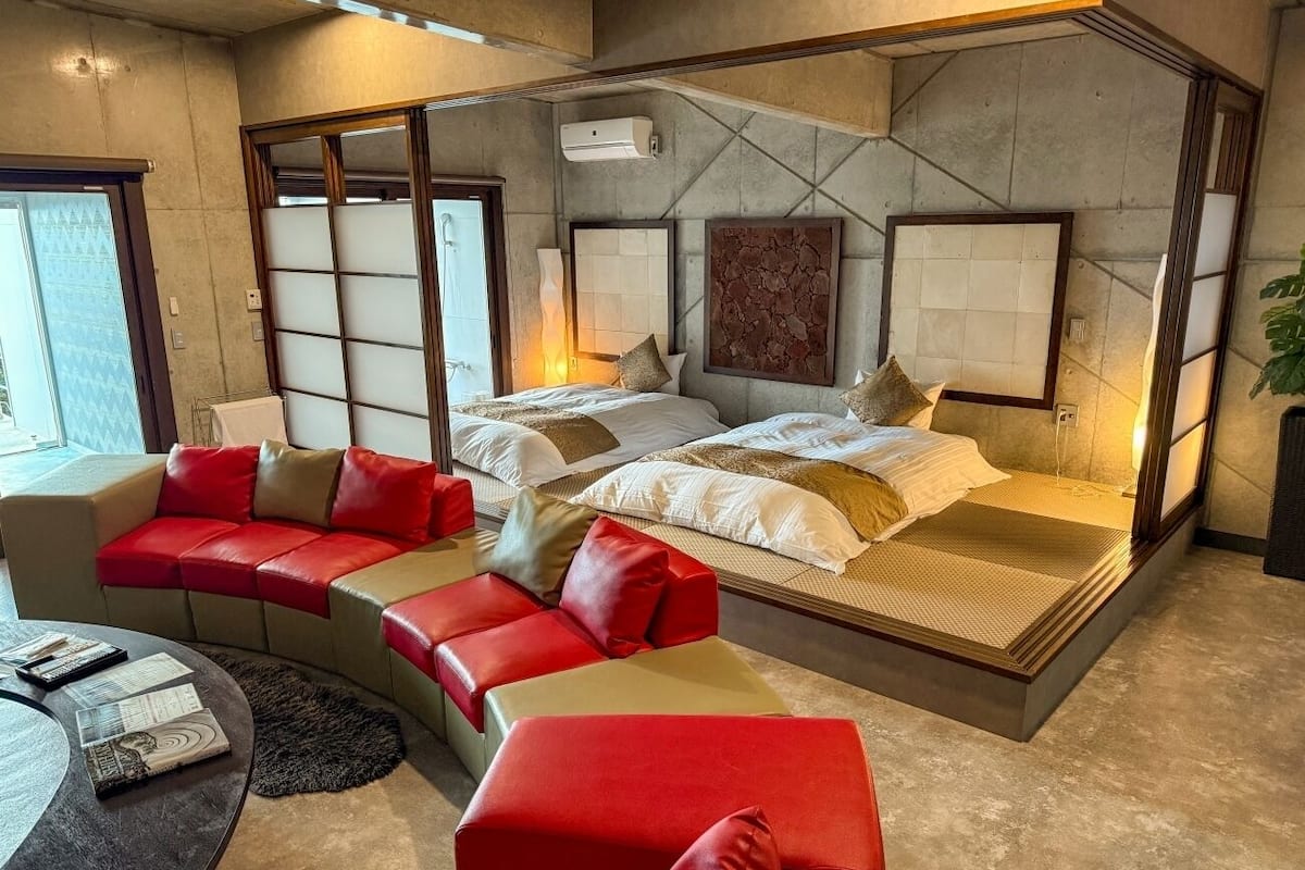 A modern hotel room with a large bed, a sofa, and a small round table.