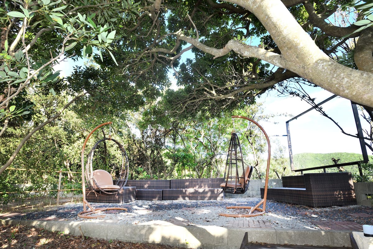 A garden with a swing set, seating area, and a view of a hilly landscape.