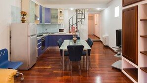 A modern kitchen with a dining area, a spiral staircase, and a flat-screen TV. - Apartment " Marina Freedom" with Wi-Fi, Air Conditioning, Balcony & Terrace (Cagliari)