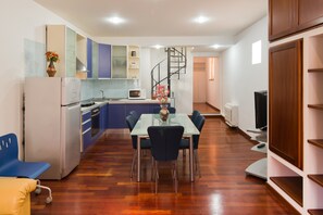 Una cocina moderna con comedor, una escalera en espiral y un televisor de pantalla plana.