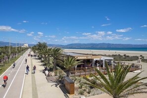 A coastal promenade with a beach, a café, and a bike lane.