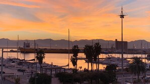 A marina with boats, a tall structure, and mountains in the background. - Apartment " Marina Freedom" with Wi-Fi, Air Conditioning, Balcony & Terrace (Cagliari)