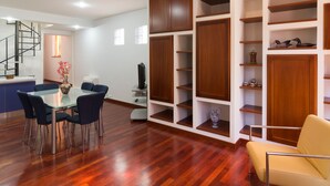 A modern interior with a dining area, built-in wooden shelving, and a staircase. - Apartment " Marina Freedom" with Wi-Fi, Air Conditioning, Balcony & Terrace (Cagliari)