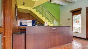 Ein Empfangsbereich mit einem Holzbüro, einer grünen Treppe und einem gefliesten Boden.