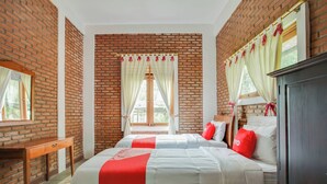 Ein Schlafzimmer mit zwei Betten, einem Holztisch und Backsteinwänden.