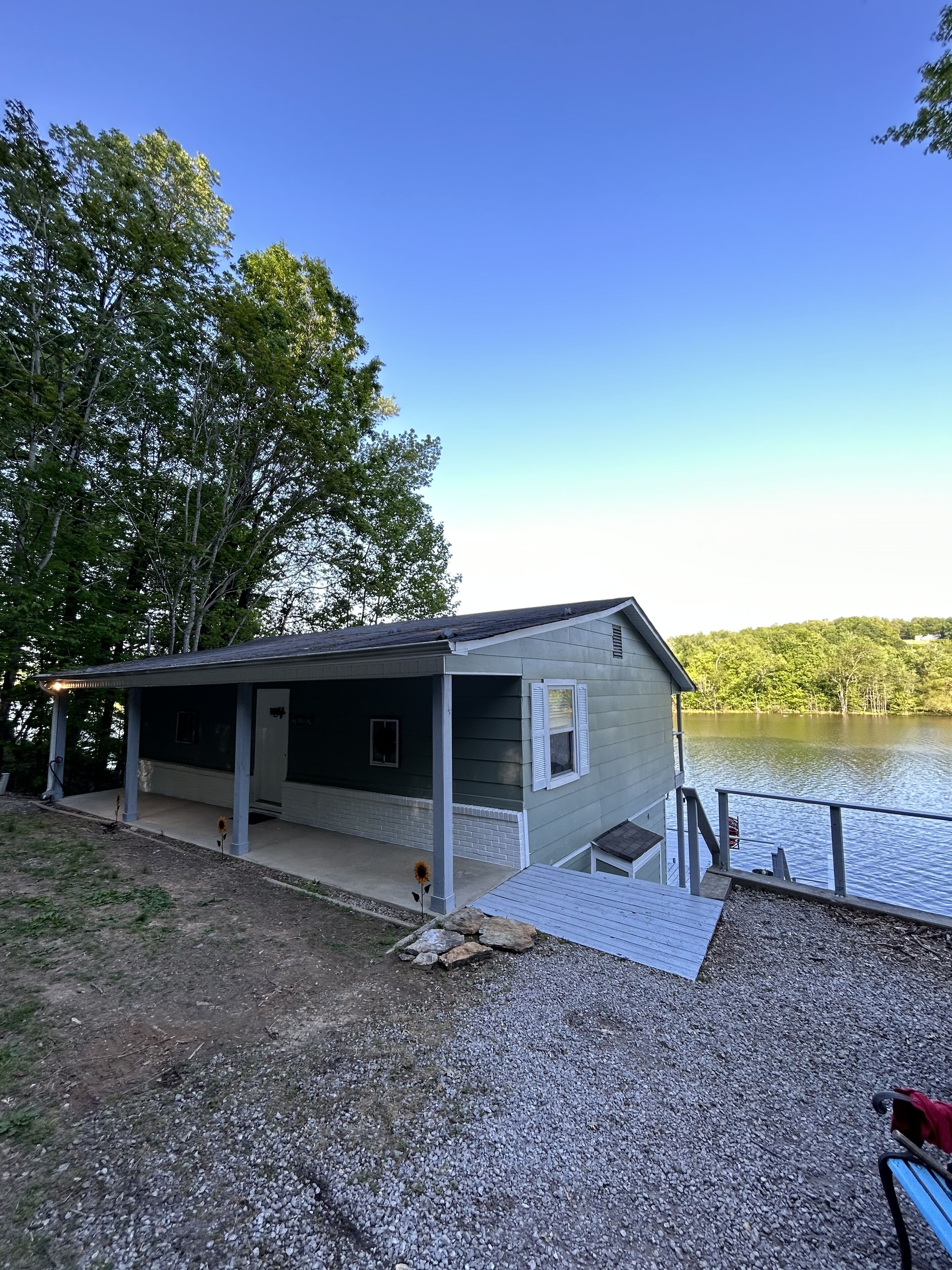 A cabin by a lake with a covered porch and a dock extending into the water.