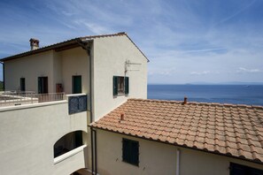 Un edificio costero con techo de tejas, balcón y vista al mar.