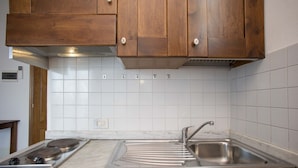 A kitchen with wooden cabinets, a stainless steel sink, and a tiled backsplash.