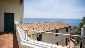 A balcony with a tiled roof overlooking the sea.