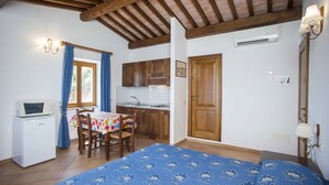 A compact room with a bed, a small kitchenette, a dining table, and a wooden ceiling. - RESIDENZA LA SCOGLIERA - MONO N° 8 LA SCOGLIERA (Rio Marina)