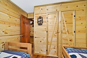 Une piĂšce en bois avec deux lits, une armoire et une lanterne suspendue.
