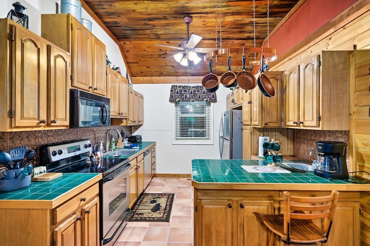 A kitchen with wooden cabinets, a microwave, stove, and hanging pots.