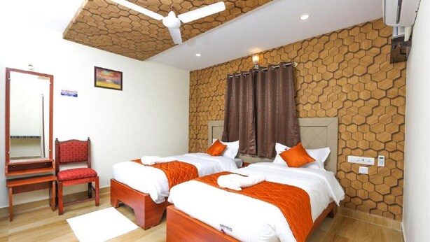 A hotel room with two beds, a wooden ceiling, a mirror, and a red chair.