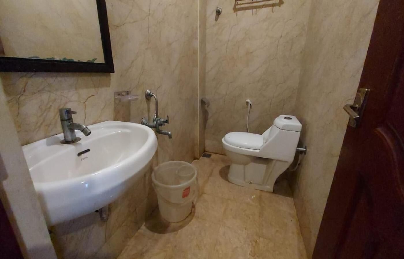 A small bathroom with a white sink, a toilet, and a trash bin.