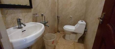 A small bathroom with a white sink, a toilet, and a trash bin.