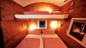Eine Hütte mit zwei Betten, darunter ein Etagenbett und ein Fenster mit Jalousien.