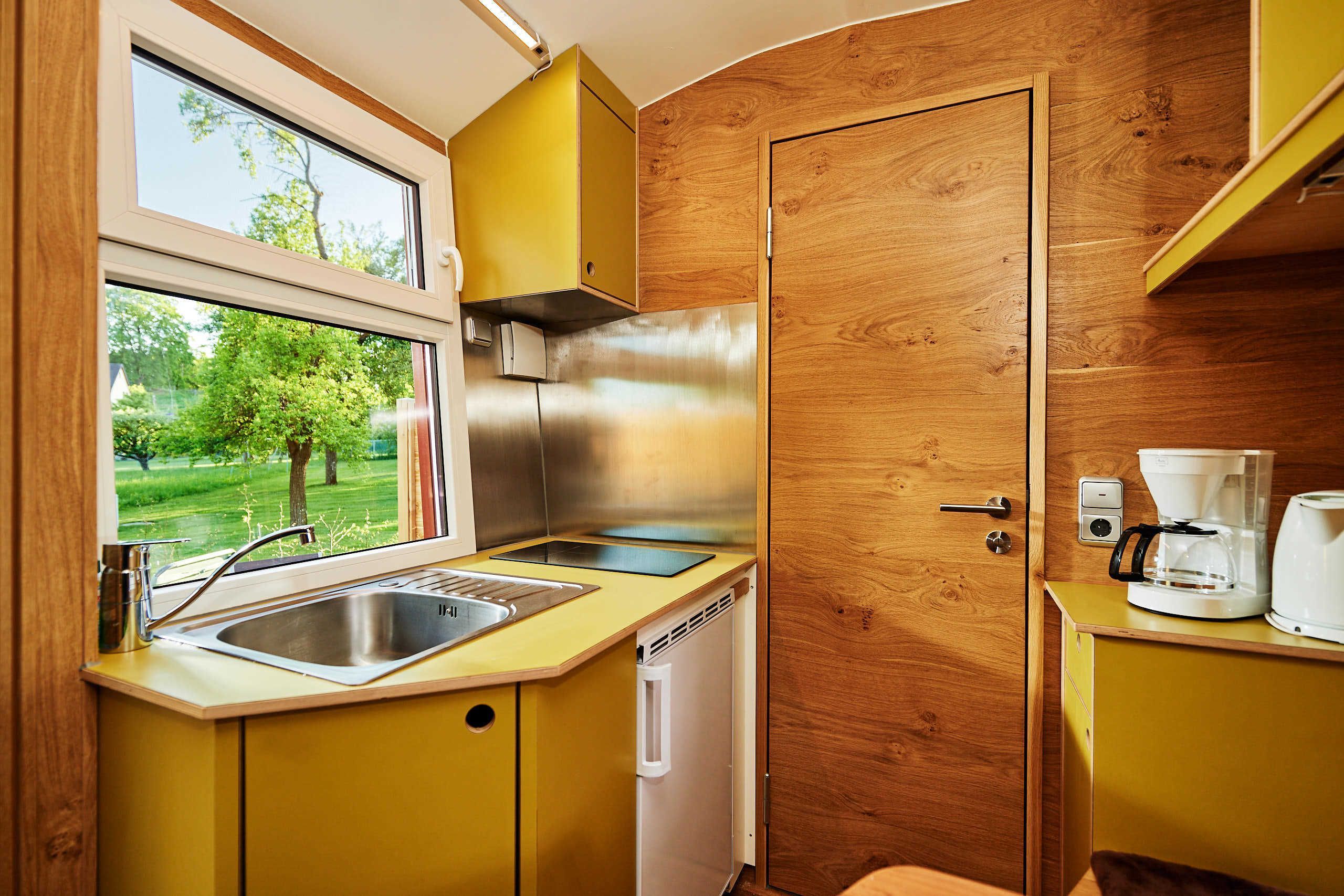 A compact kitchen with a stainless steel refrigerator, a sink, and a coffee maker.