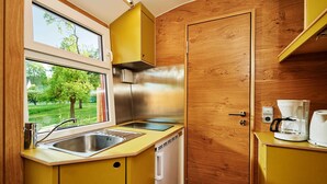 Eine kleine Küche mit einem Edelstahlkühlschrank, einer Spüle und einer Kaffeemaschine.
