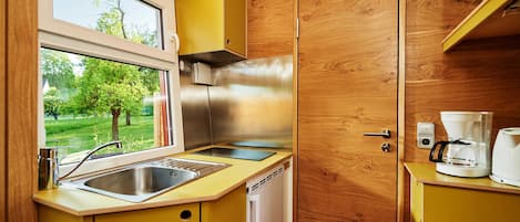 A compact kitchen with a stainless steel refrigerator, a sink, and a coffee maker.