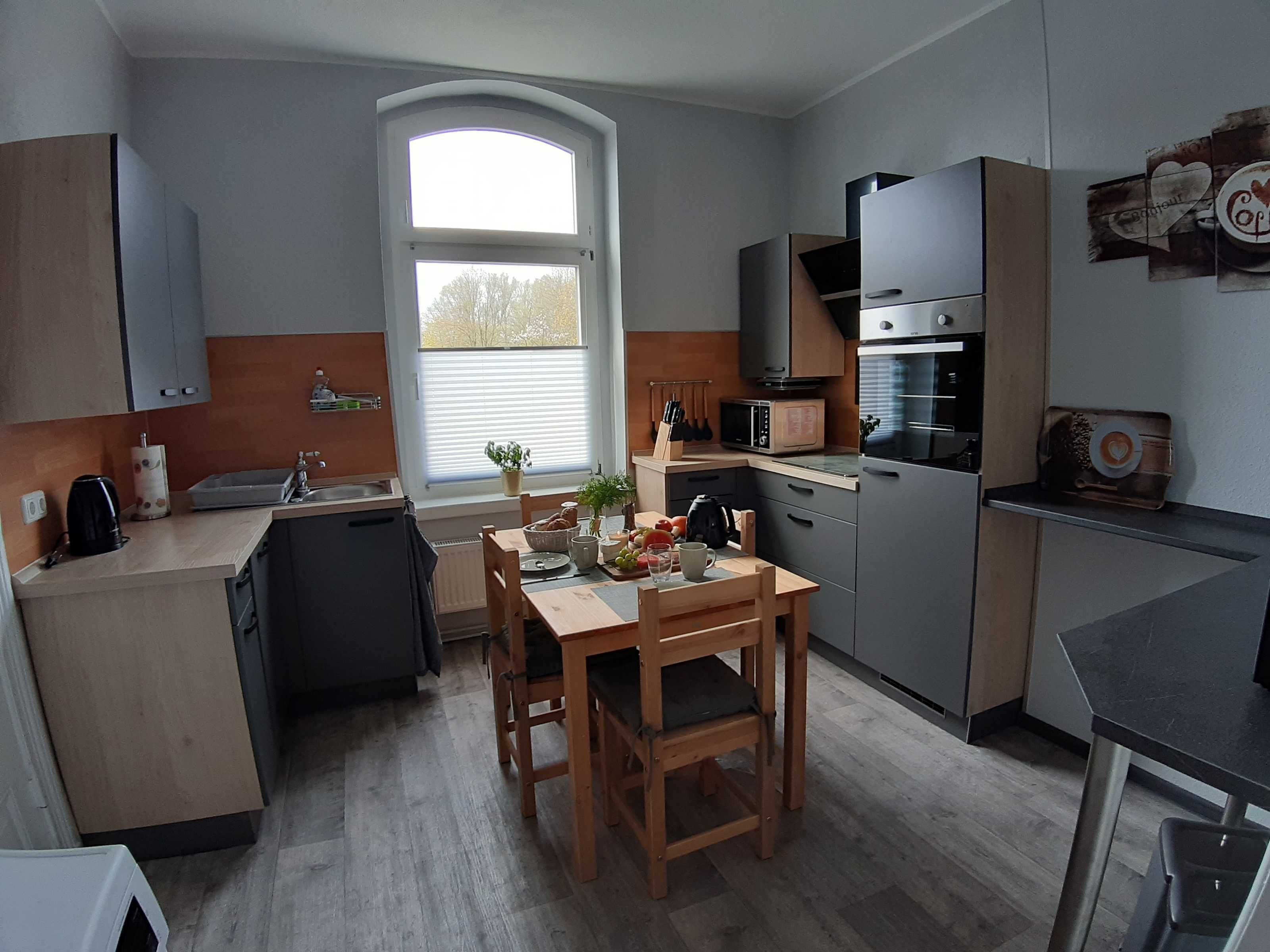 Eine moderne Küche mit Essbereich, einer Mikrowelle, einem Herd und einem Fenster mit Jalousien.