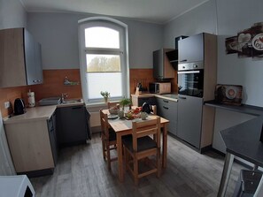 A modern kitchen with a dining area, a microwave, a stove, and a window with blinds.