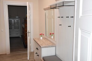 Une pièce avec une coiffeuse en bois, un miroir et une porte donnant sur un couloir.