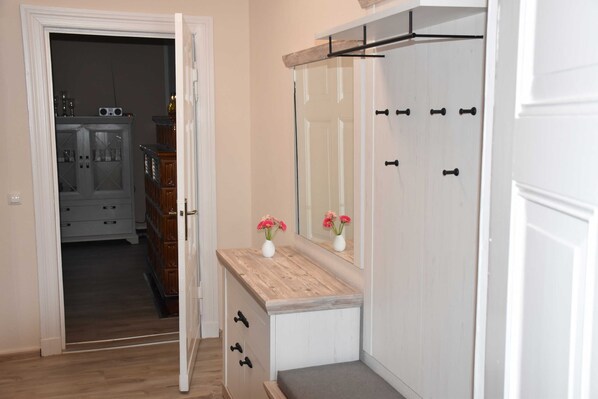 A room with a wooden vanity, a mirror, and a door leading to a hallway.
