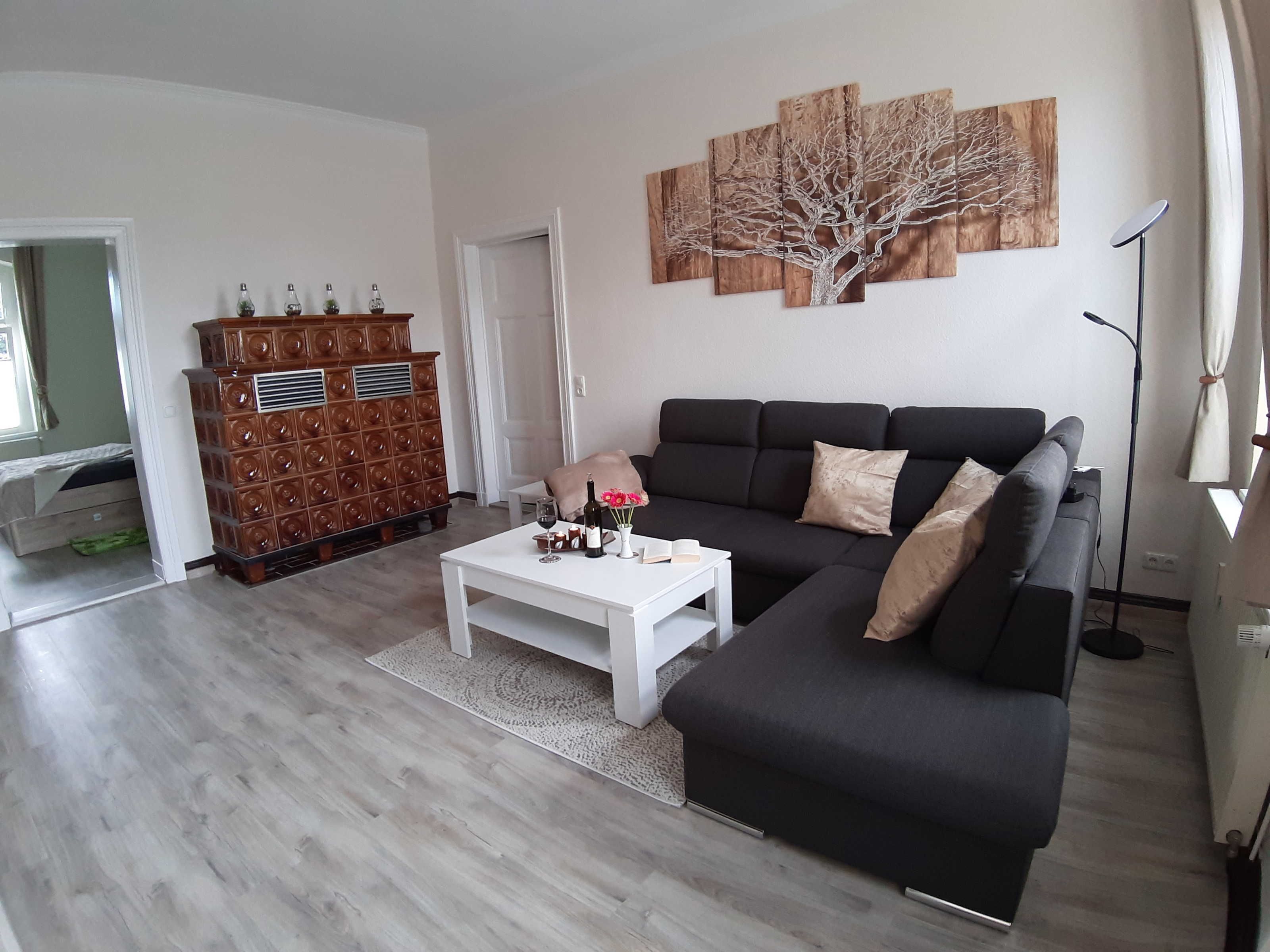 Ein Wohnzimmer mit einer schwarzen Couch, einem weißen Couchtisch und einem Holzschrank.