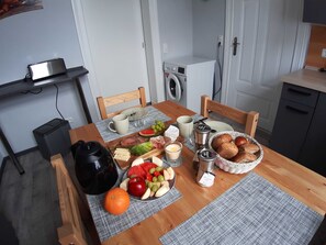Une table à manger avec de la nourriture, une machine à café et un lave-linge en arrière-plan.