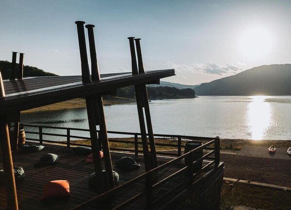 A wooden deck with exercise balls, overlooking a calm lake with mountains in the background. - Radika Rezort (Leunovo)