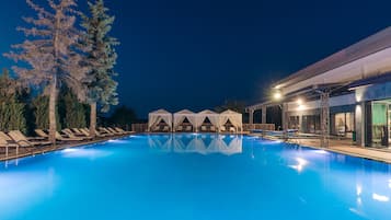 Una piscina cubierta, una piscina al aire libre, sombrillas, tumbonas