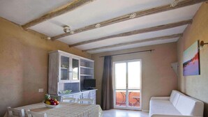 Un coin repas avec une table dressée pour deux personnes, un buffet blanc aux portes vitrées et un canapé.