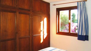 Une chambre à coucher avec un lit, une armoire en bois et une fenêtre avec des rideaux.