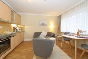 A modern kitchen with wooden cabinets, a built-in oven, and a dining area with a table and chairs.
