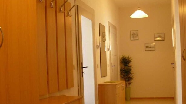 A hallway with wooden cabinets, a plant, and framed pictures on the wall. - Ferienwohnung Herrmann (Weischlitz)