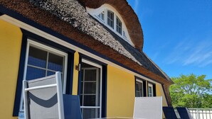 A room with a thatched roof, a yellow wall, and a window with a white frame. - Buchfink, Deutschland (Prerow)