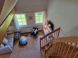 A spacious living area with a sofa, a coffee table, a chair, a TV, and a staircase.
