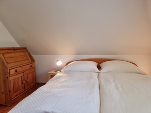 Ein Schlafzimmer mit einem Holzkapfen, einer Nachttischlampe und einem Bett mit weißer Bettwäsche.
