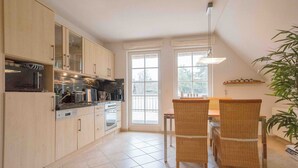 A kitchen with a dining area, large windows, and a plant. - Buchfink, Deutschland (Prerow)