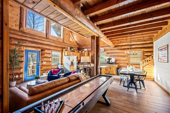L’intérieur d’une cabane en rondins, avec une table de billard, un canapé et un coin repas.