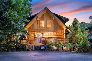 Une cabane en rondins avec une façade en bois, une véranda et une porte bleue.