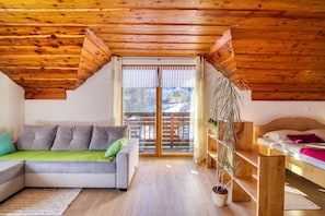 Une pièce chaleureuse avec un plafond en bois, un canapé agrémenté de coussins, une petite table et une plante en pot.