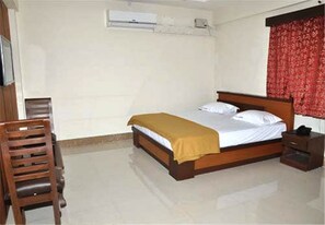 A bedroom with a bed, a chair, a nightstand, and a red curtain. - SL Park Kallakurichi (Kallakkurichi)