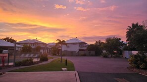 A residential street during sunset with houses, a sidewalk, and a street lamp. - Lillypilly Resort Apartments (Gracemere)