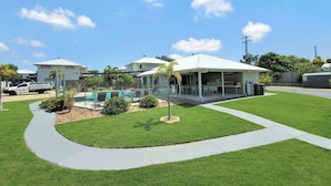 A residential area with a swimming pool, a covered patio, and a well-maintained lawn. - Lillypilly Resort Apartments (Gracemere)