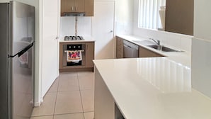A modern kitchen with a refrigerator, stove, oven, and dishwasher. - Lillypilly Resort Apartments (Gracemere)