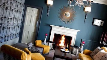 Una sala de estar con chimenea, pared con estampado y muebles amarillos.