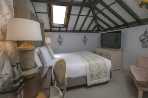A bedroom with a bed, a desk, a chair, a TV, and decorative wall art.