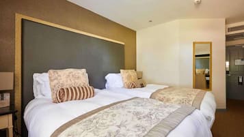 Habitación de hotel con dos camas, un espejo grande y un pequeño escritorio con una lámpara.